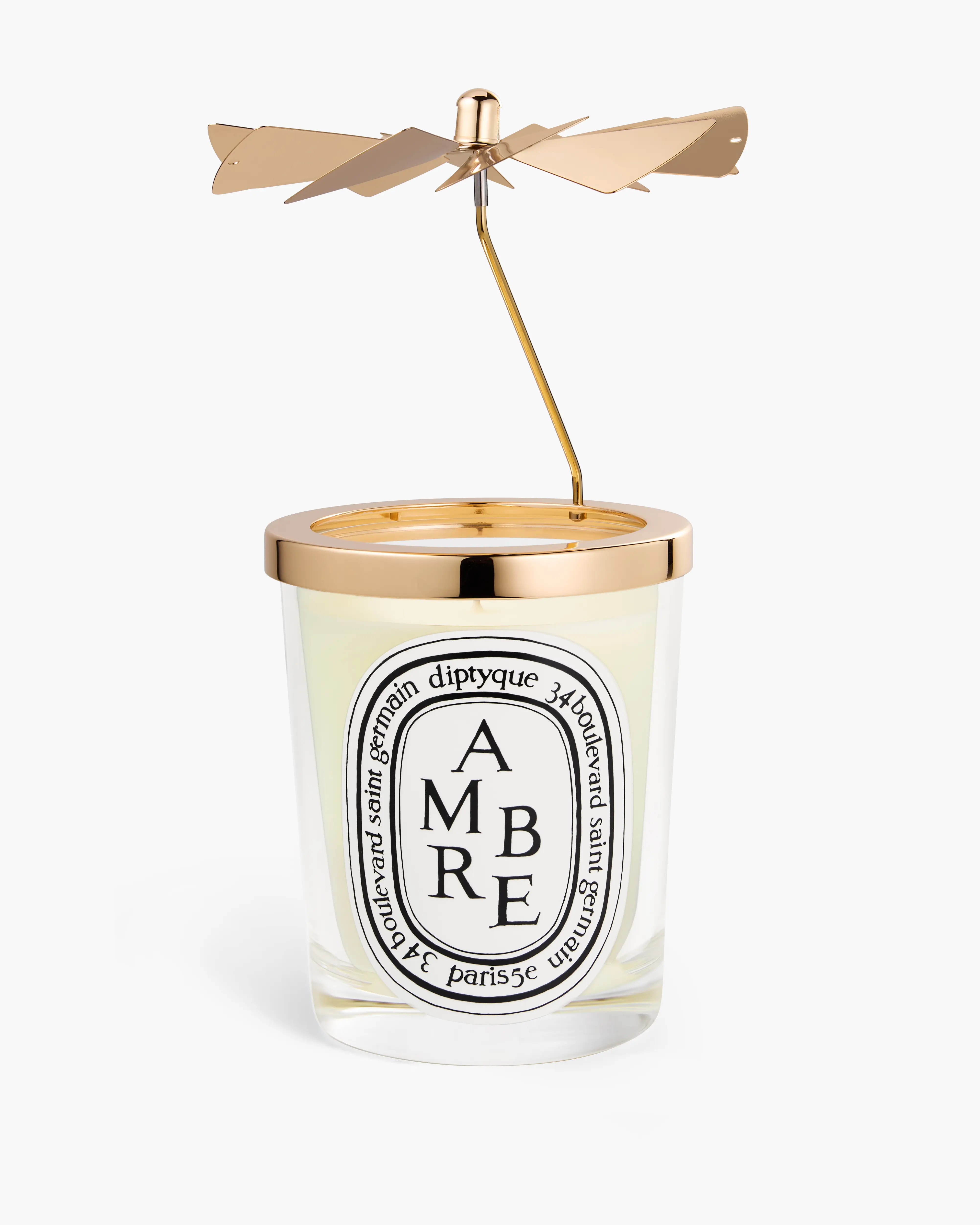 Bougie parfumée Diptyque Ambre avec un support doré et hélice décorative au-dessus.